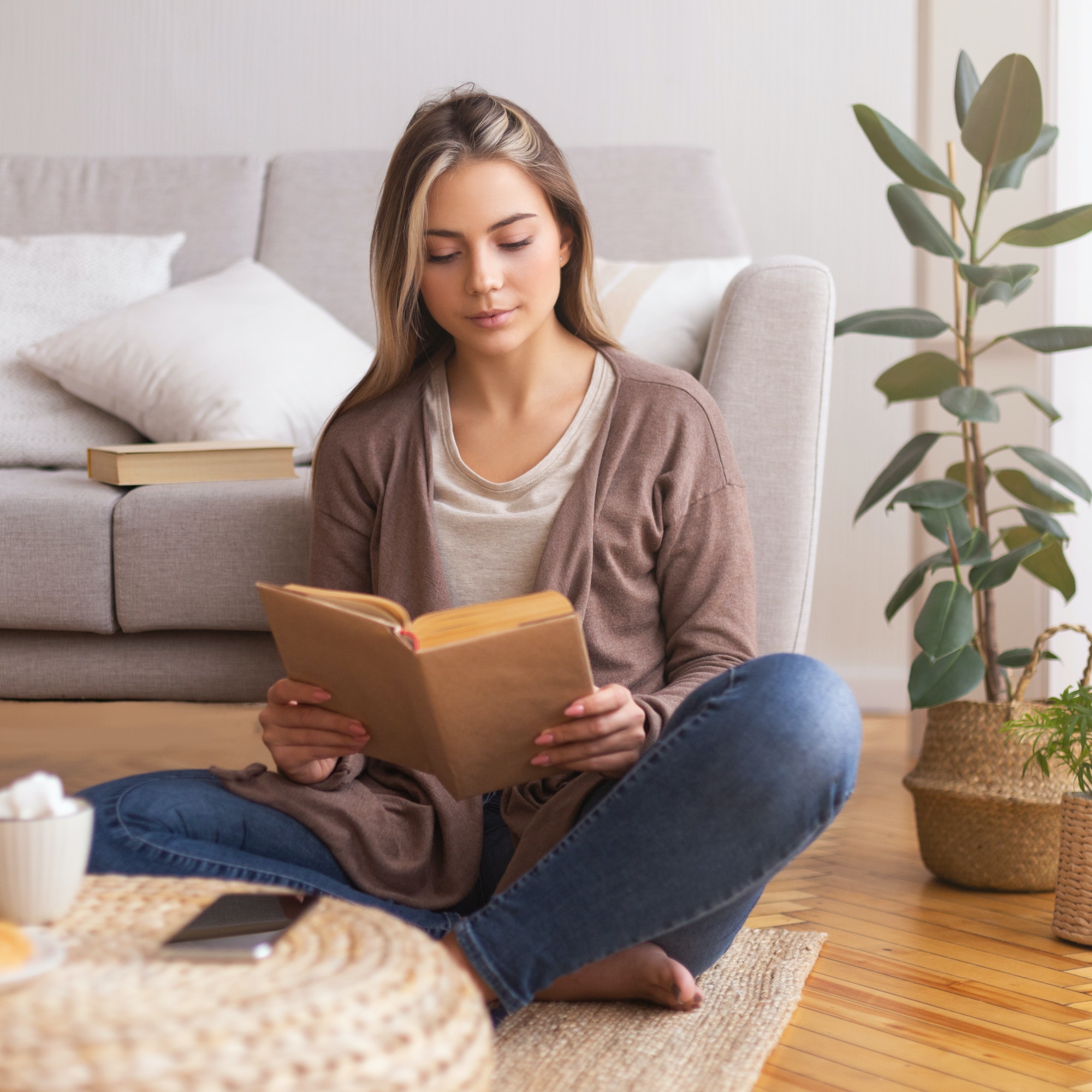 Beautiful young woman reading book on floor