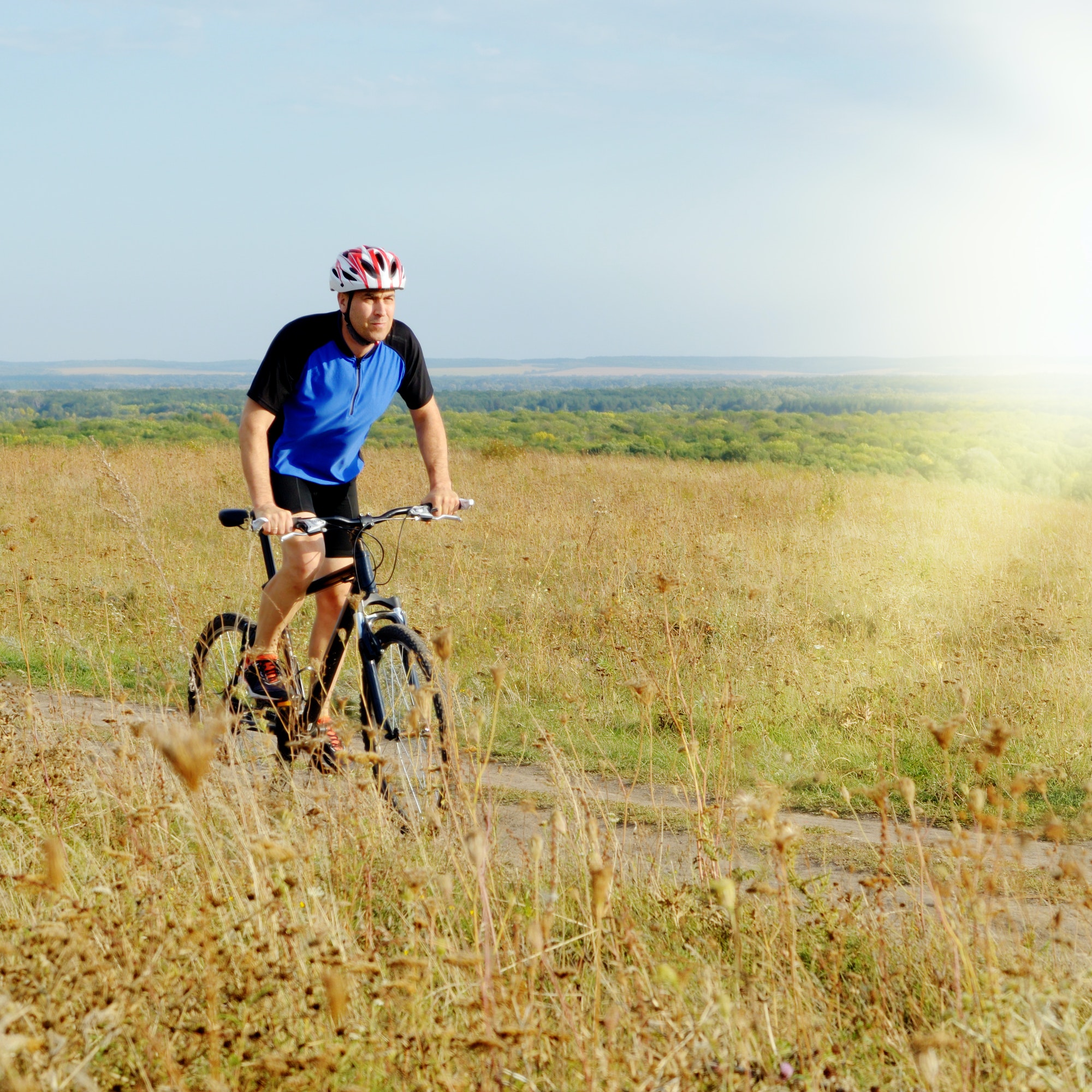 Male cyclist driving by rural dirt road outdoors